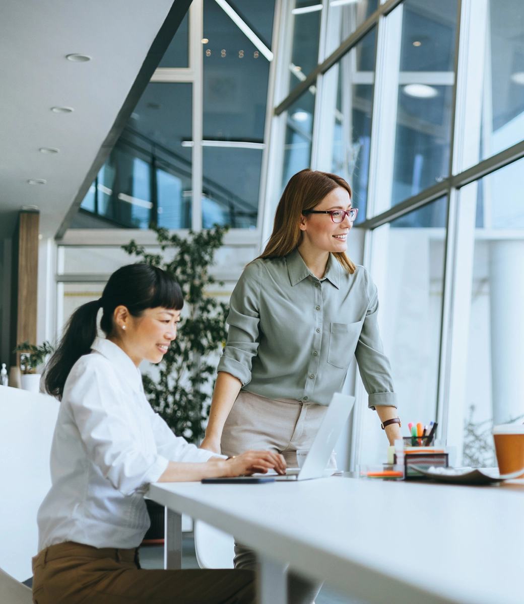 Moderne Glasfassade mit Büros, umgeben von Bäumen, sonniger Tag