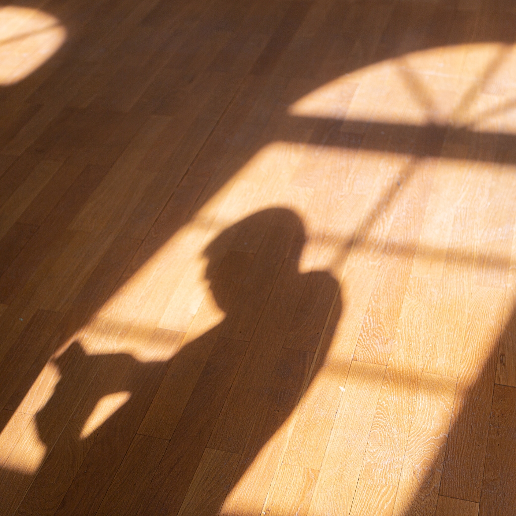 Schatten einer Person fotografiert auf sonnigen Holzboden