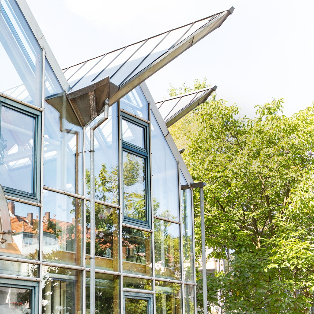 Modernes Gebäude mit vielen Fenstern, umgeben von Bäumen