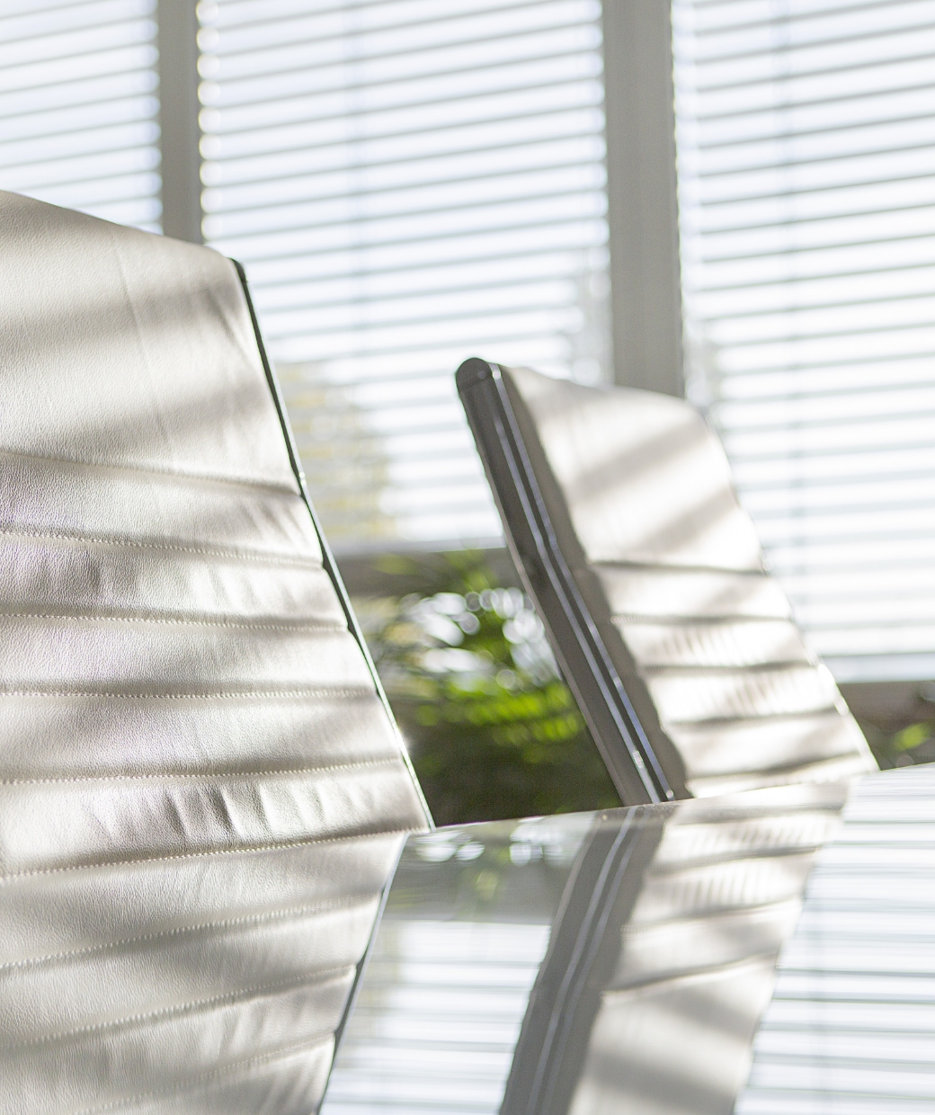 Zwei leere Bürostühle spiegeln sich auf dem Konferenztisch