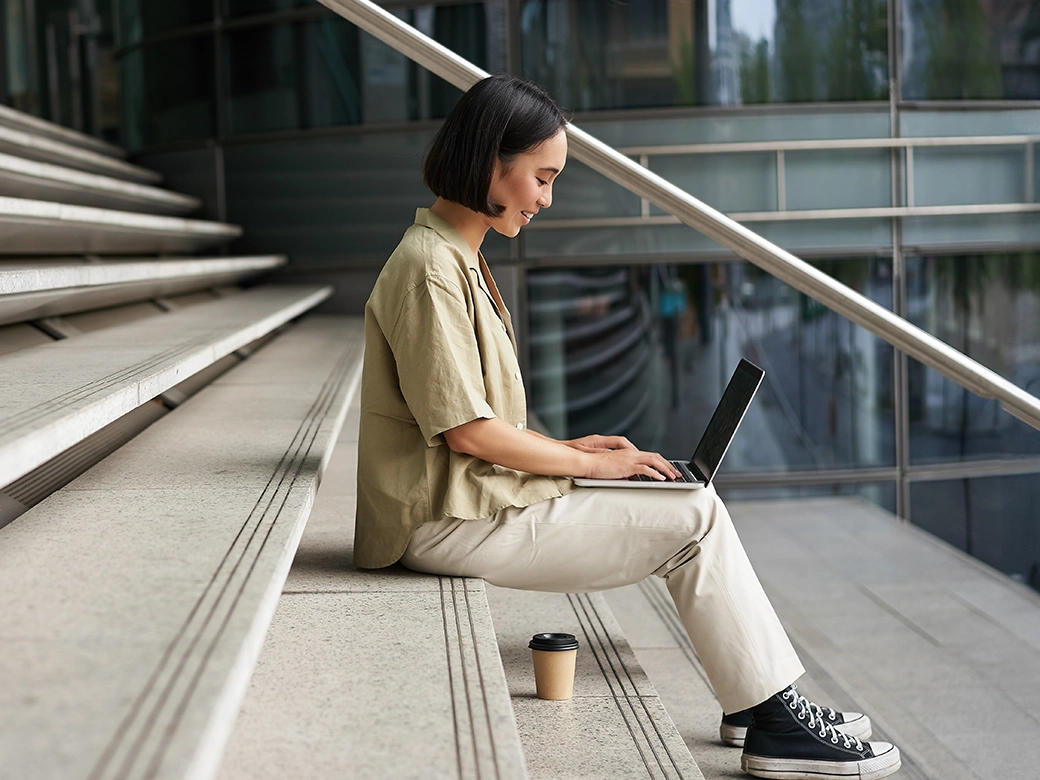 Person arbeitet am Schreibtisch unter Dachfenster in modernem Büro