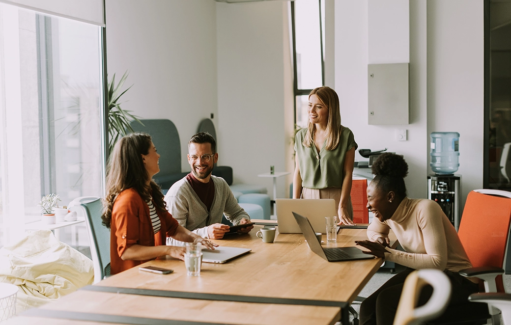Zwei Männer unterhalten sich lächelnd im modernen Büro über online Lohnabrechnungen