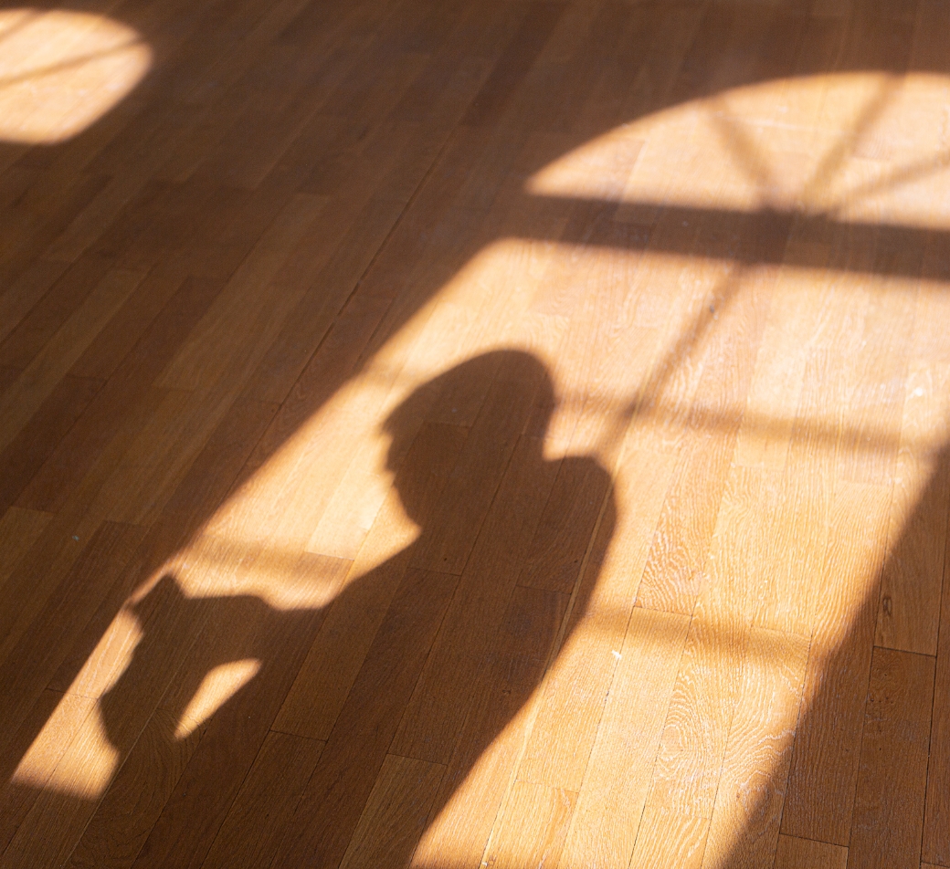 Schatten einer Person auf Holzfußboden im Sonnenlicht