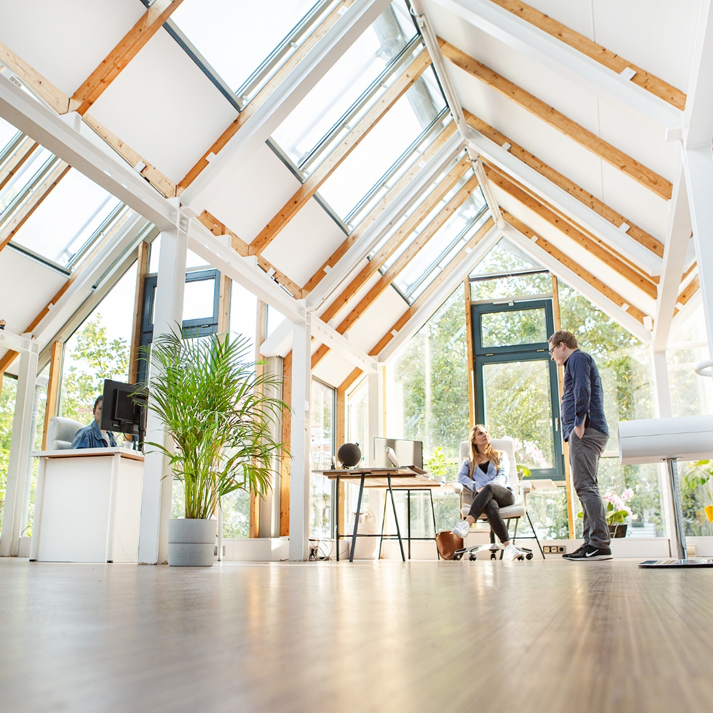 Personen diskutieren in einem hellen, modernen Büro mit Glasdach