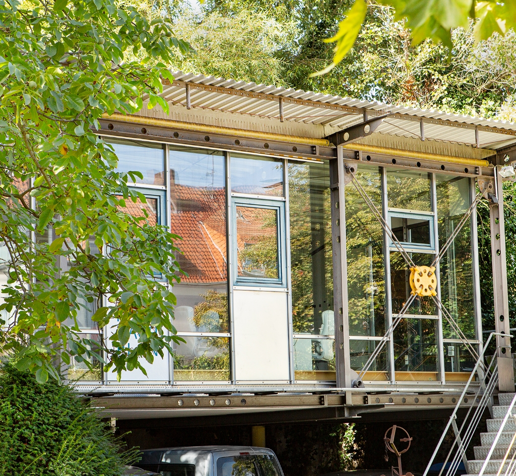 Modernes Bürogebäude mit Glasfront, umgeben von Bäumen