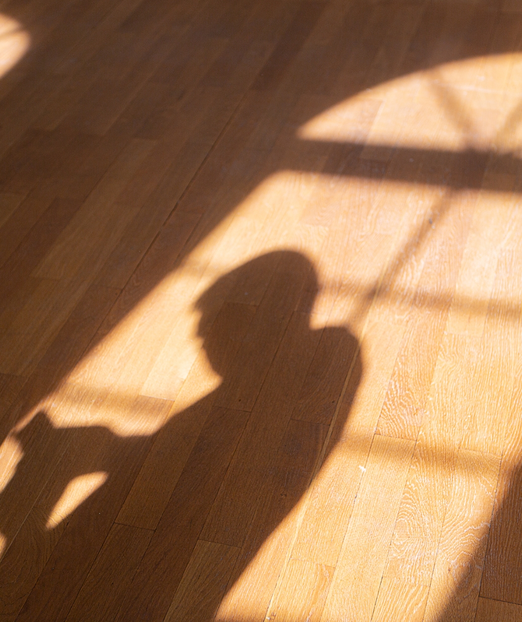 Schatten einer Person auf Holzboden durch Sonnenlicht