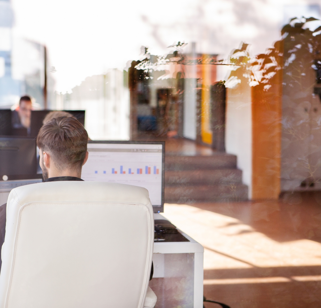 Person arbeitet am Computer, Büro im Hintergrund sichtbar
