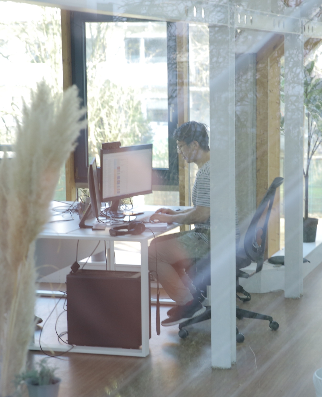 Person arbeitet am Computer in modernem Büro mit Glaswänden