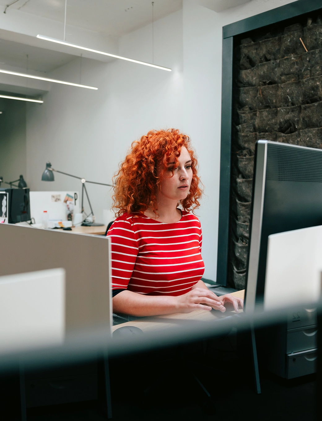 Lächelnde Personen arbeiten gemeinsam an einem Computer im Büro an Urlaubsgeld-Berechnungen