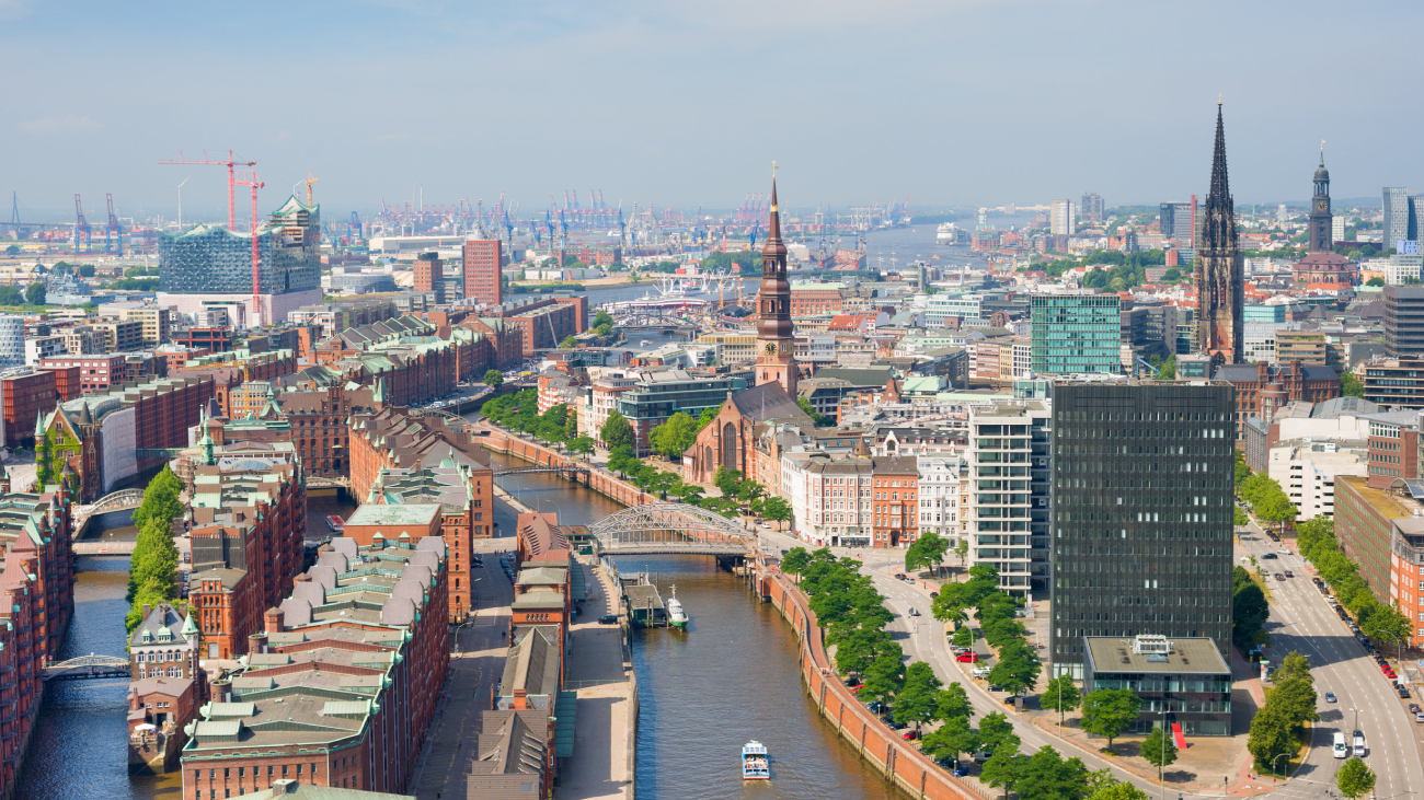Lohnabrechnung Hamburg: Stadtansicht mit Fluss und historischen Gebäuden bei sonnigem Wetter