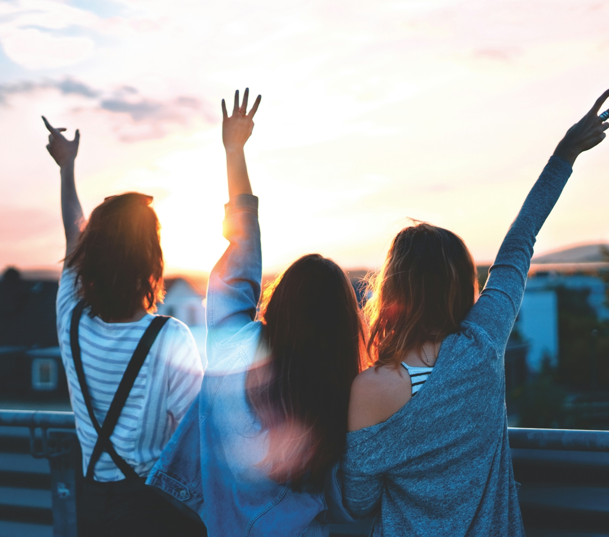 Drei Personen jubeln, stehen auf Balkon im Sonnenuntergang