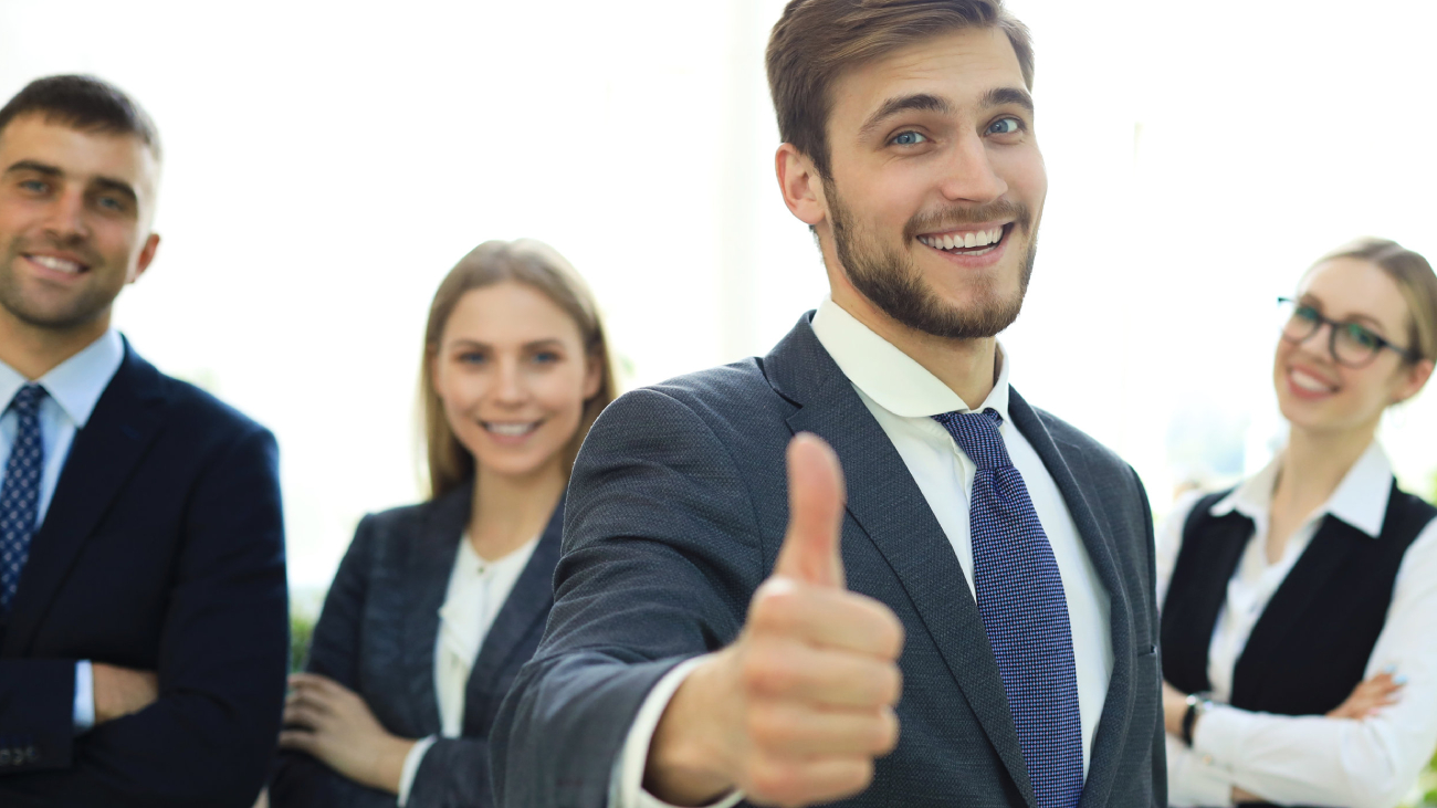 Lohnabrechnung Dresden: Gruppe lächelnder Menschen, Daumen hoch, im Büro
