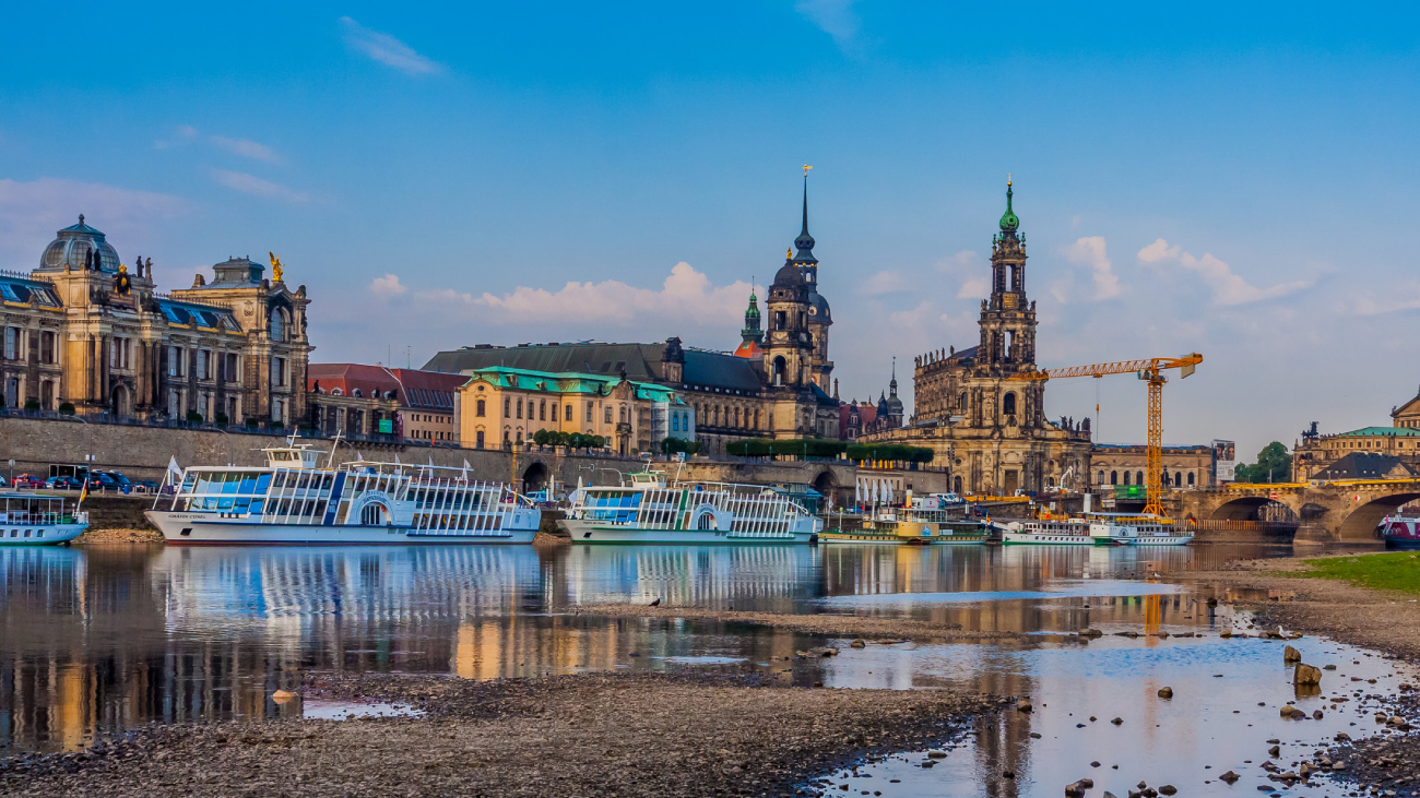 Lohnabrechnung Dresden: Boote ruhen am Ufer, historische Gebäude im Hintergrund