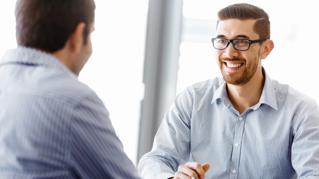 Lohnabrechnung Dresden: Zwei lächelnde Männer im Gespräch in einem Büro