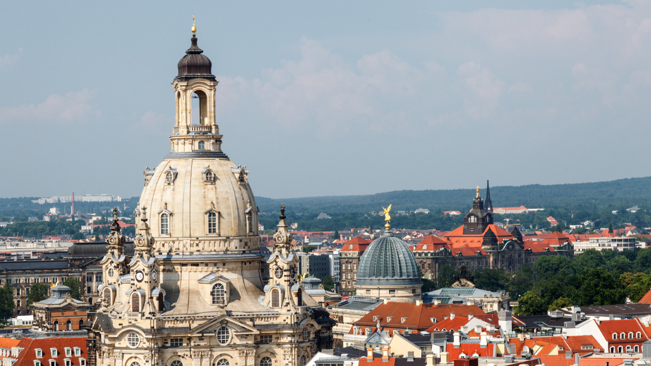 Lohnabrechnung Dresden: Kirchturm ragt über Stadtansicht, umgeben von historischen Gebäuden