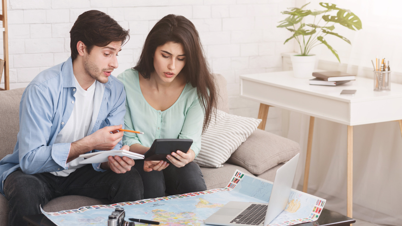 Lohnabrechnung Düsseldorf: Zwei Personen prüfen Dokumente, sitzen auf Sofa mit Laptop