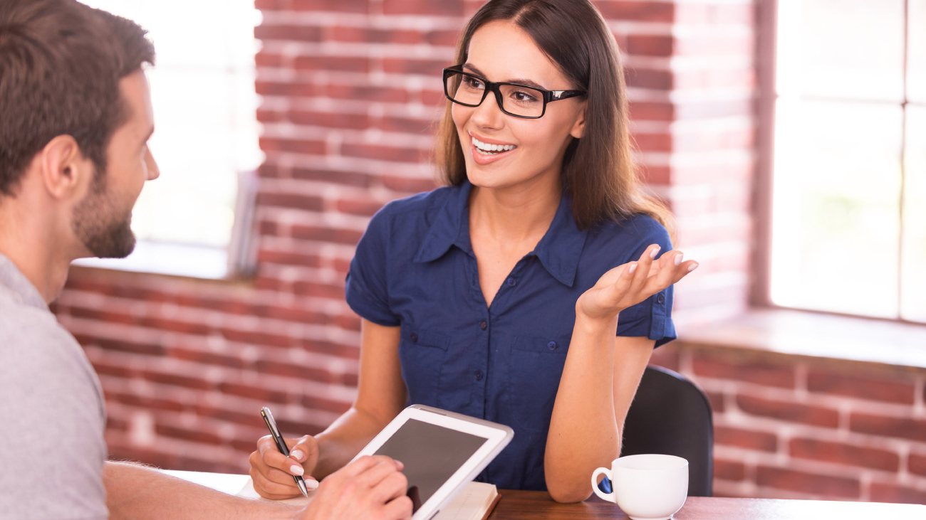 Lohnabrechnung Frankfurt: Frau spricht lächelnd mit Mann im Büro mit Backsteinwänden