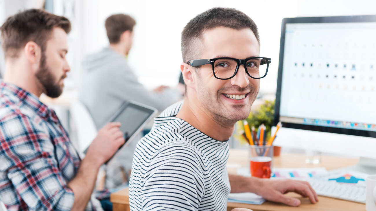 Lohnabrechnung Frankfurt: Mann lächelt, arbeitet am Computer im Büro